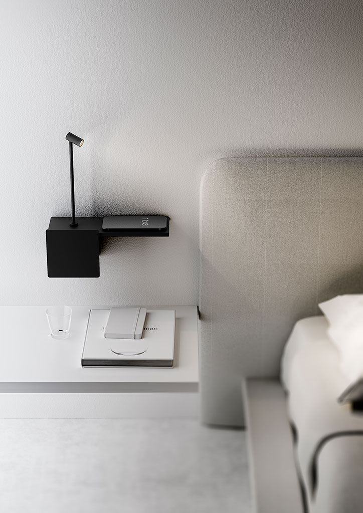 Lampada Biga nera da parete con frontalino quadrato accanto a un letto moderno