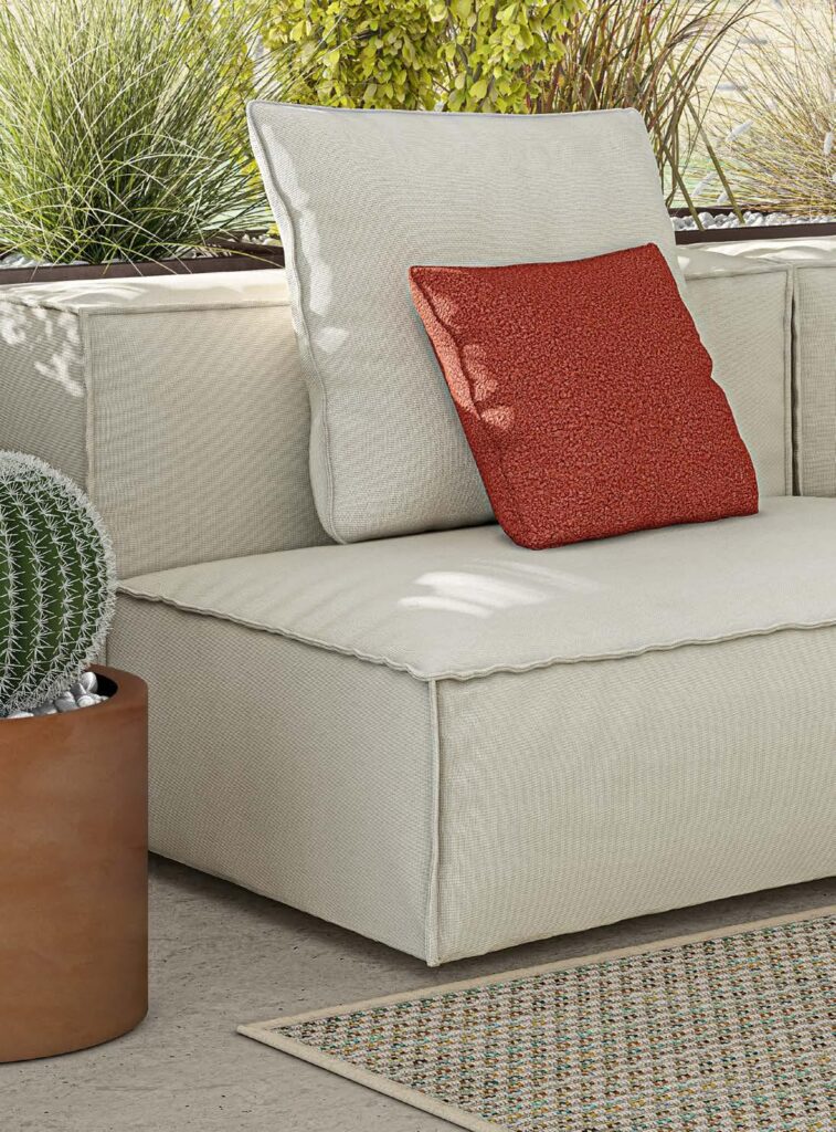 Primo piano su cuscino rosso su divano outdoor beige con vaso cactus