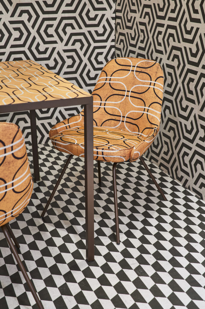 Tavolo e sedia Momenti con rivestimento geometrico arancione su sfondo realizzato in Tecno Fiber